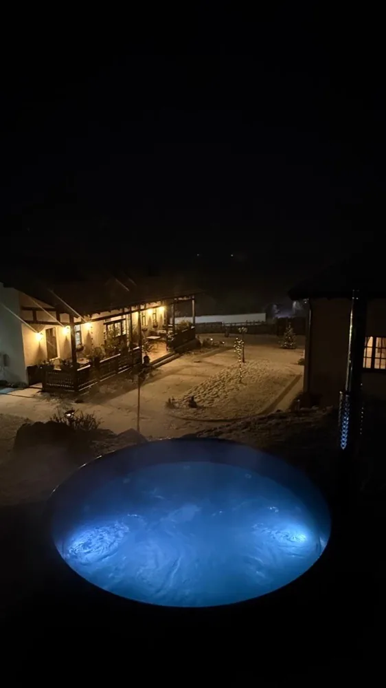 Jacuzzi în aer liber, iluminat seara, în curtea pensiunii