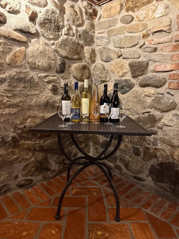 Sticle și pahare de vin pe o masă în beciul de piatră al pensiunii
